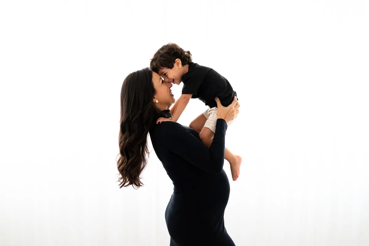 Mãe grávida com o filho ao colo