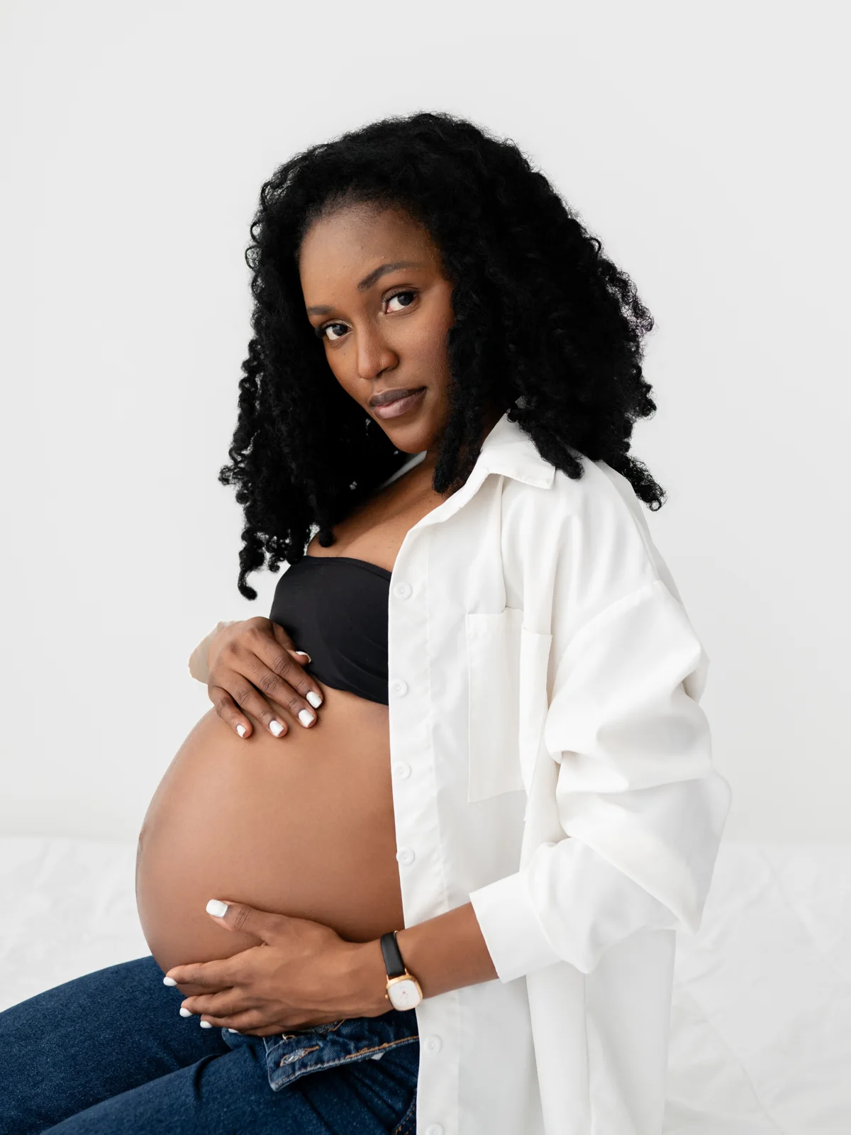 Retrato de grávida de camisa branca, mãos na barriga