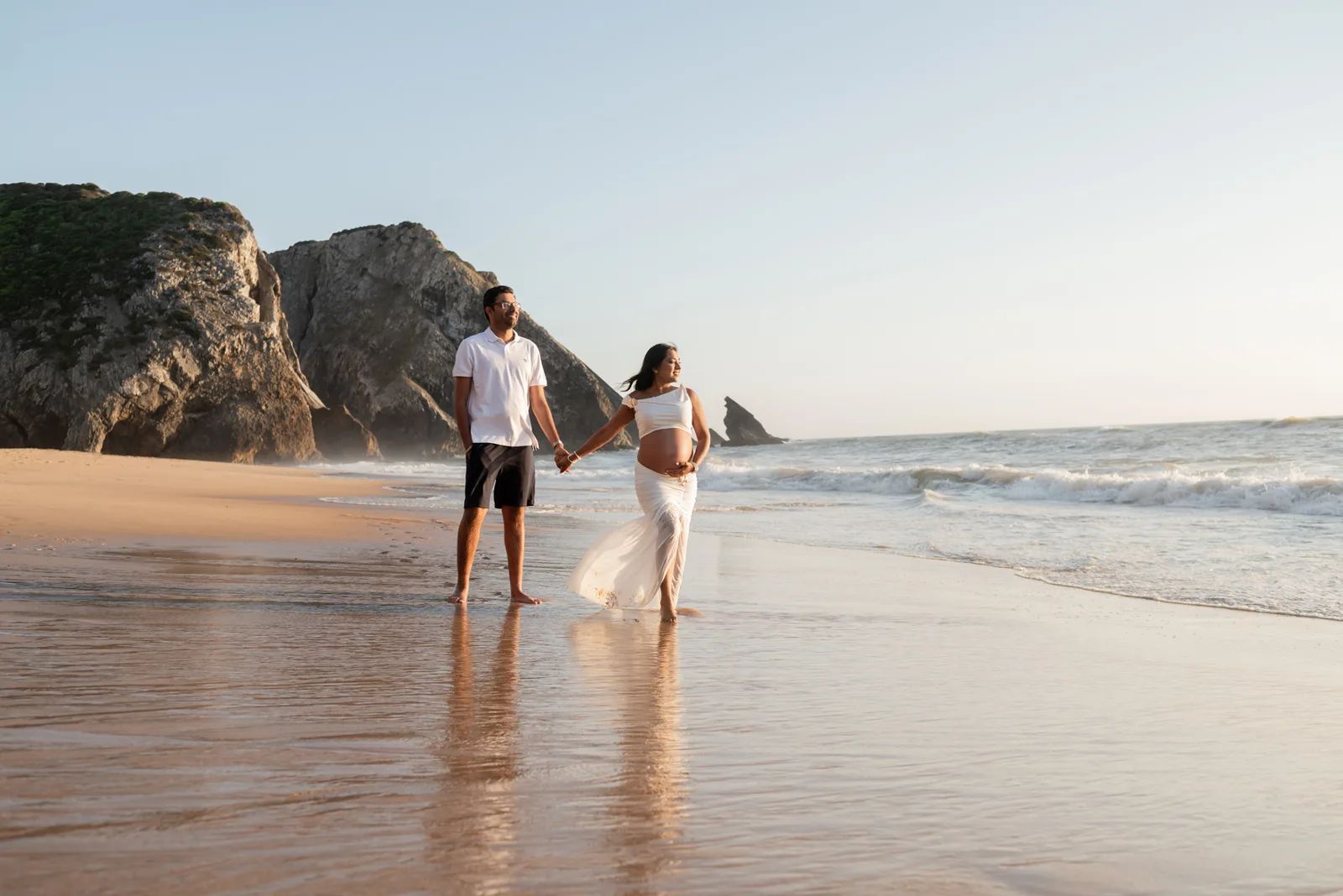 Casal de mãos dadas na praia ao fim da tarde